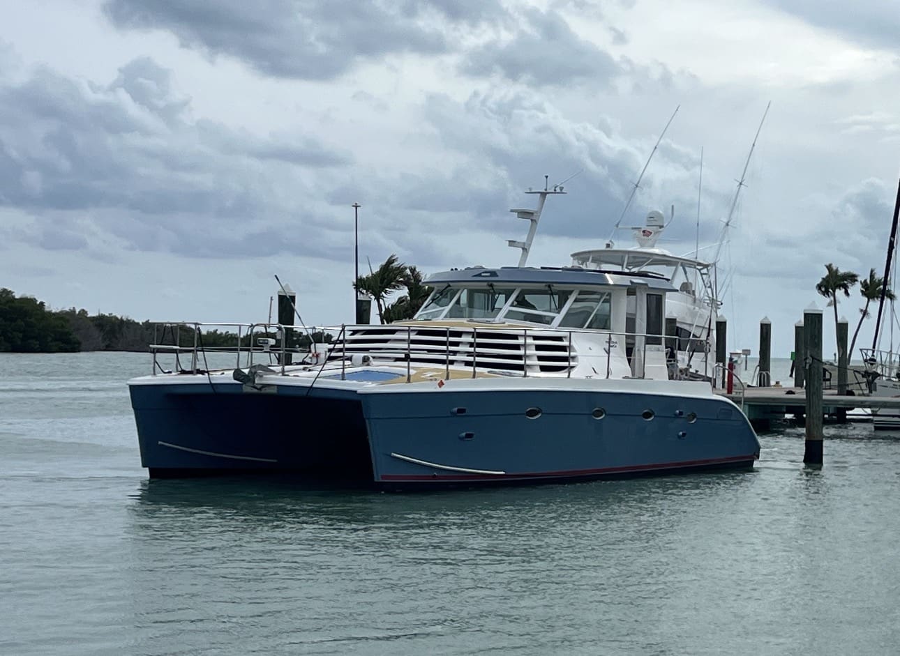 Blue catamaran yacht docked in calm harbor